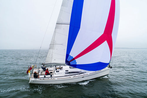 A sailboat flying a Cruising Asymmetrical Spinnaker in blue, white, and red colors.